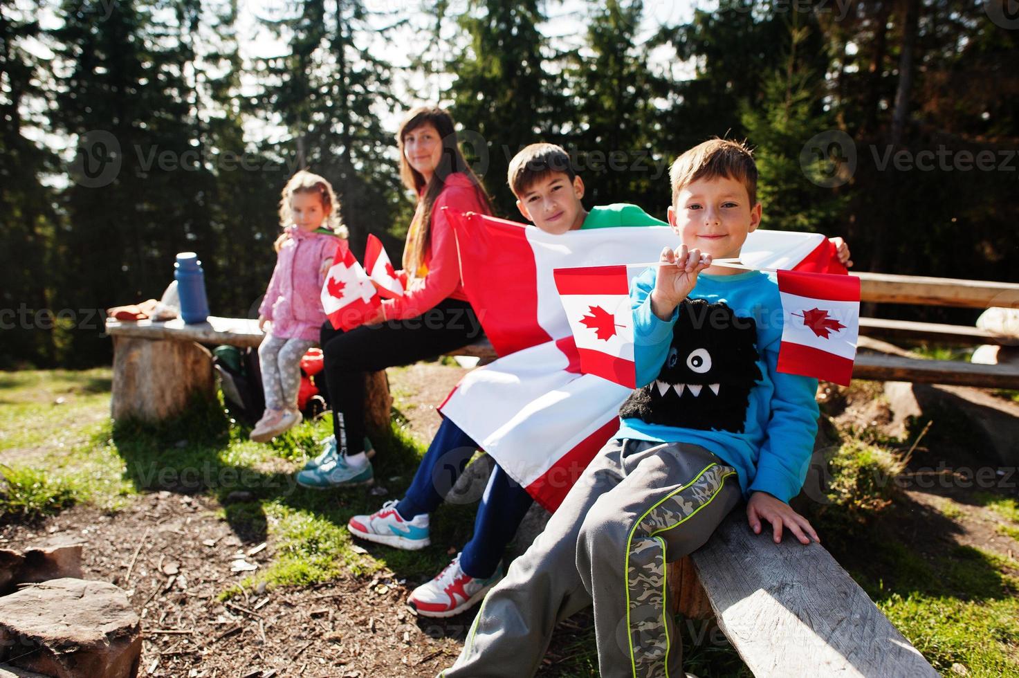 Happy Canada Day. Family of mother with three kids hold large Canadian flag celebration in mountains. photo