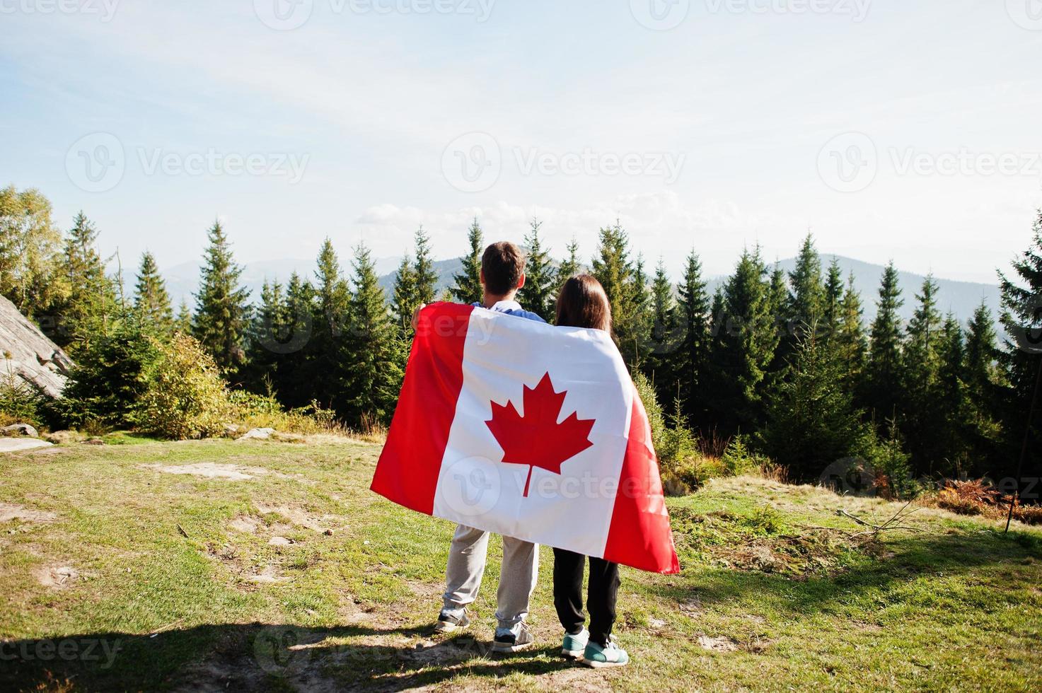 Happy Canada Day. Couple with large Canadian flag celebration in mountains. photo