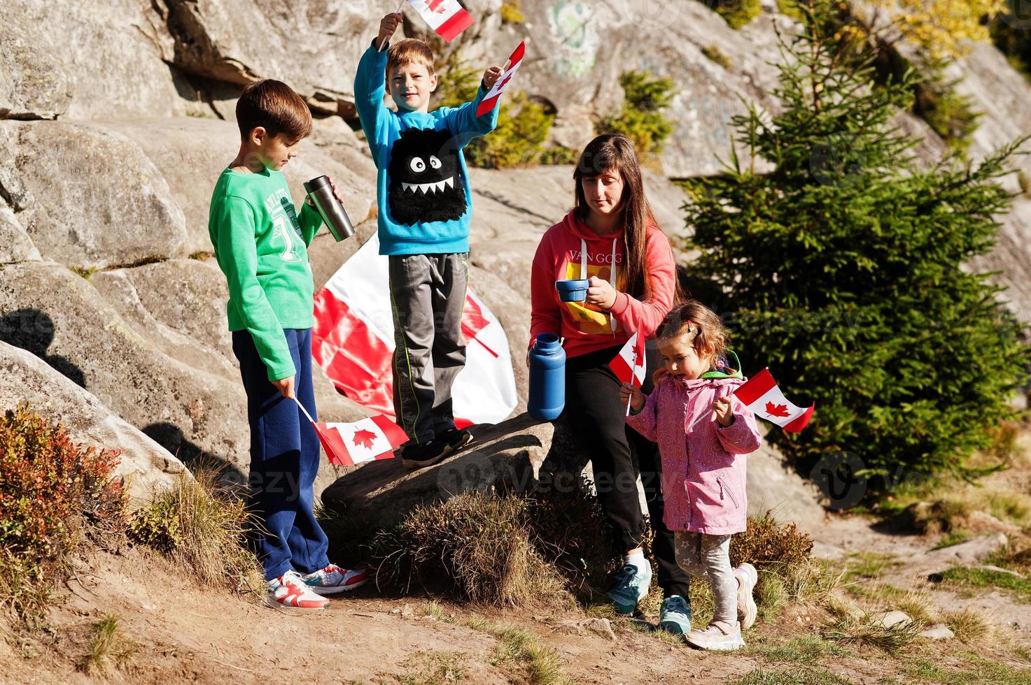 Happy Canada Day. Family of mother with three kids hold large Canadian flag celebration in mountains. photo
