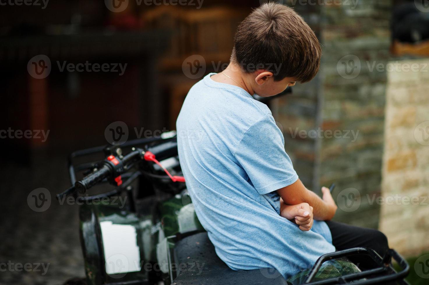 Boy in four-wheller ATV quad bike with mobile phone. photo