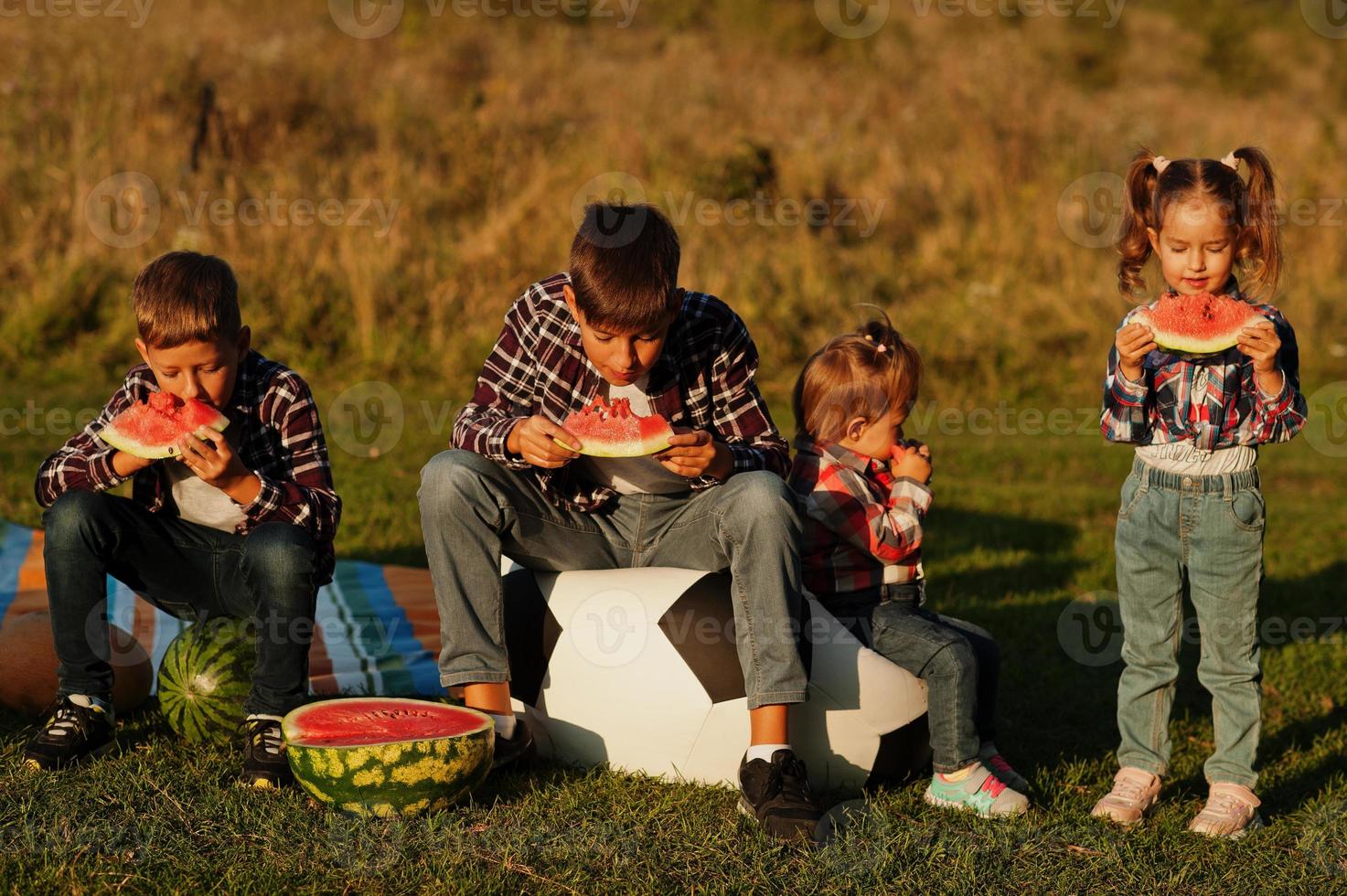 Family spending time together. Four kids eat watermelon outdoor. photo