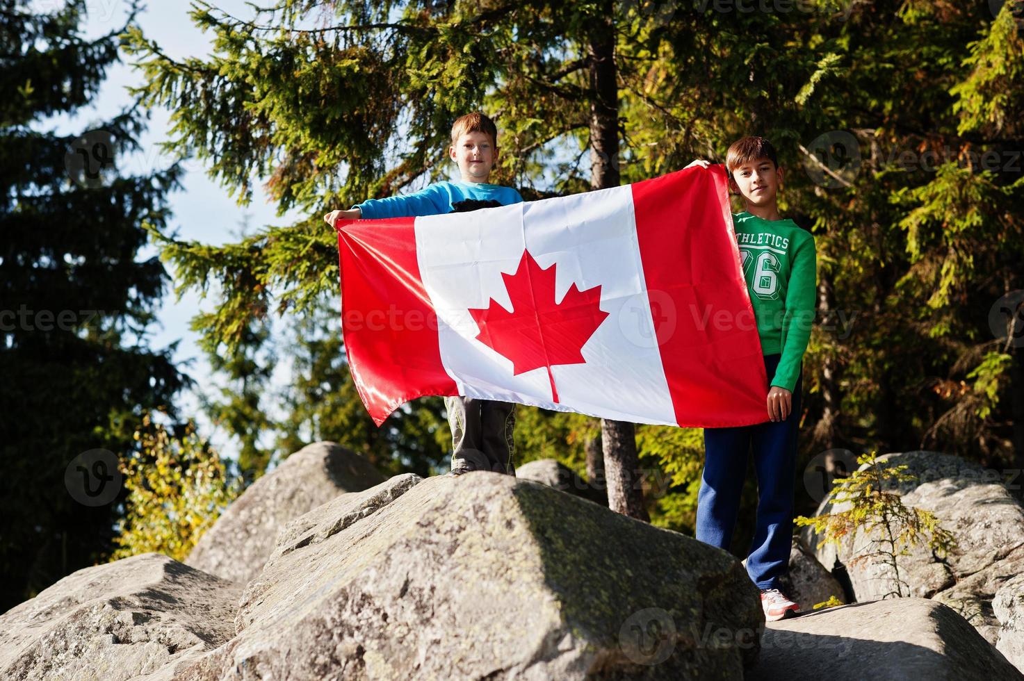 Happy Canada Day. Two brothers with large Canadian flag celebration in mountains. photo