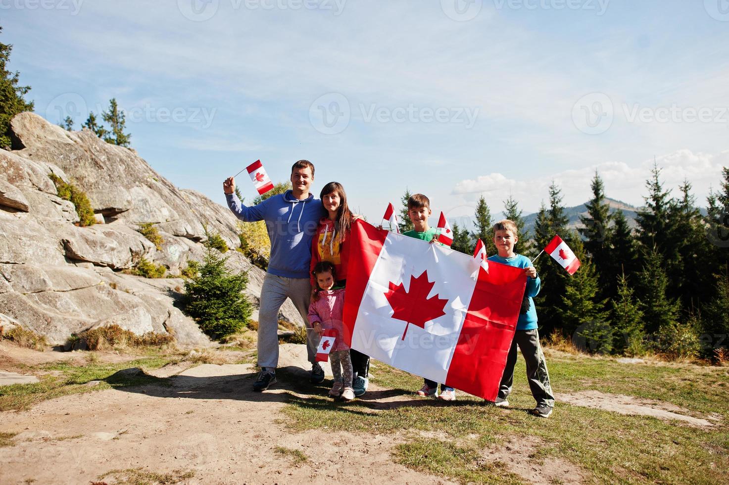 Happy Canada Day. Family with large Canadian flag celebration in mountains. photo