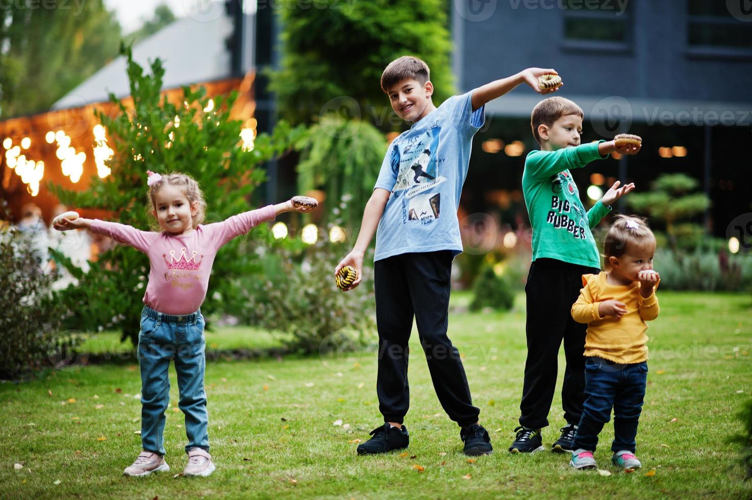 cuatro niños con donuts en el patio de la tarde. sabrosa deliciosa comida de donas. foto