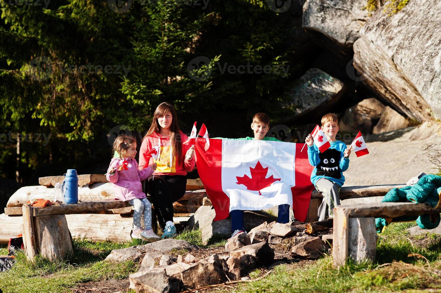 Happy Canada Day. Family of mother with three kids hold large Canadian flag celebration in mountains. photo