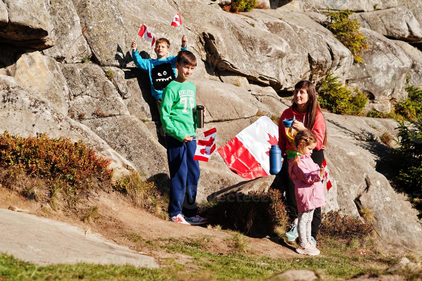 Happy Canada Day. Family of mother with three kids hold large Canadian flag celebration in mountains. photo