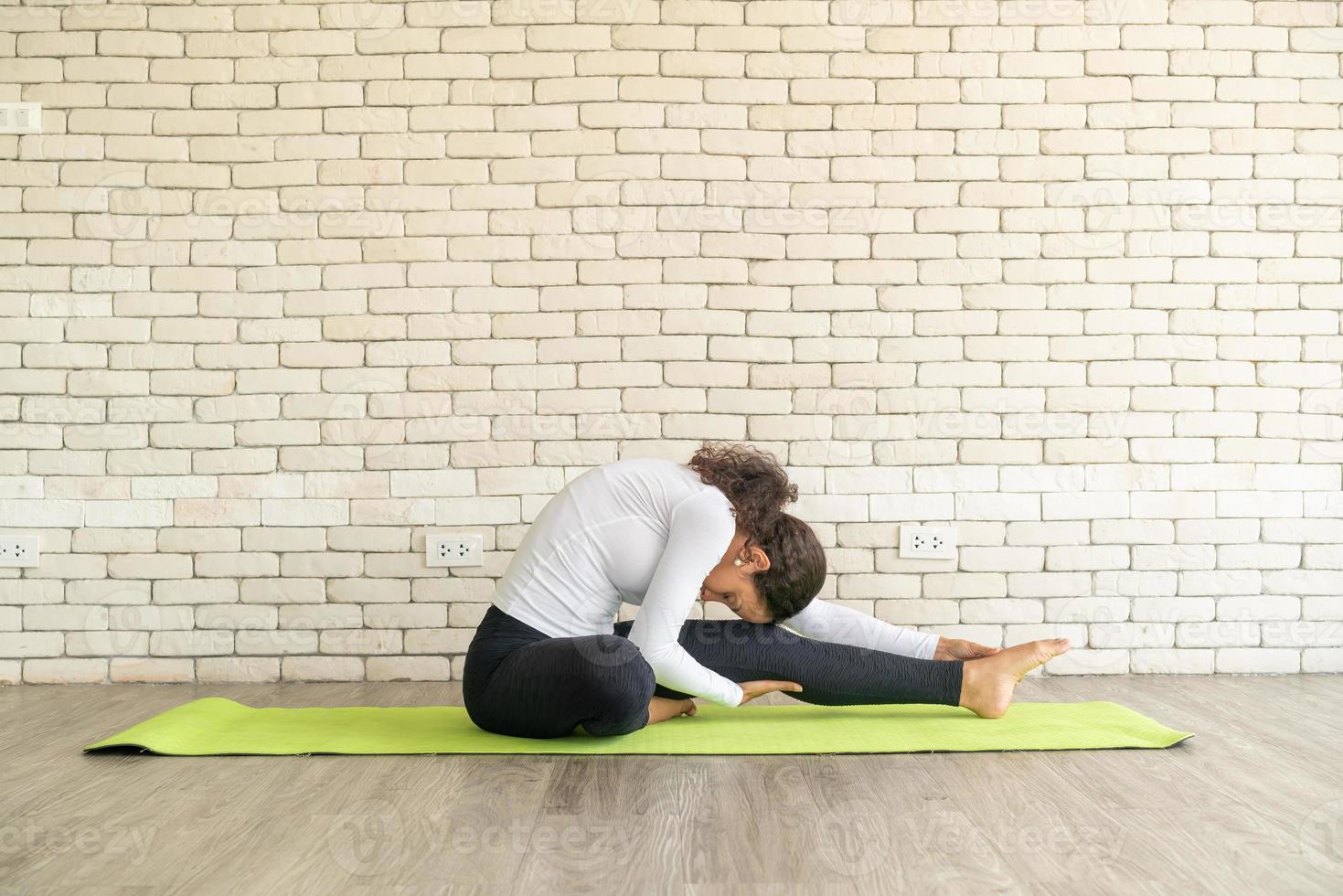 Latin woman practicing yoga on mat photo