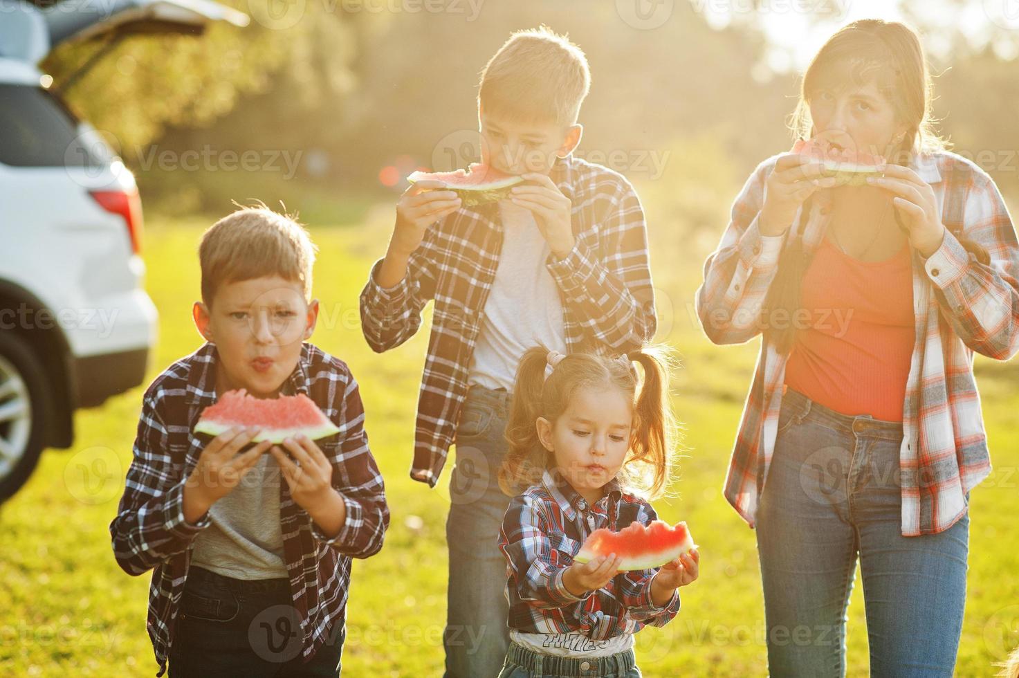 Family spending time together. Three kids with mother eat watermelon outdoor. photo