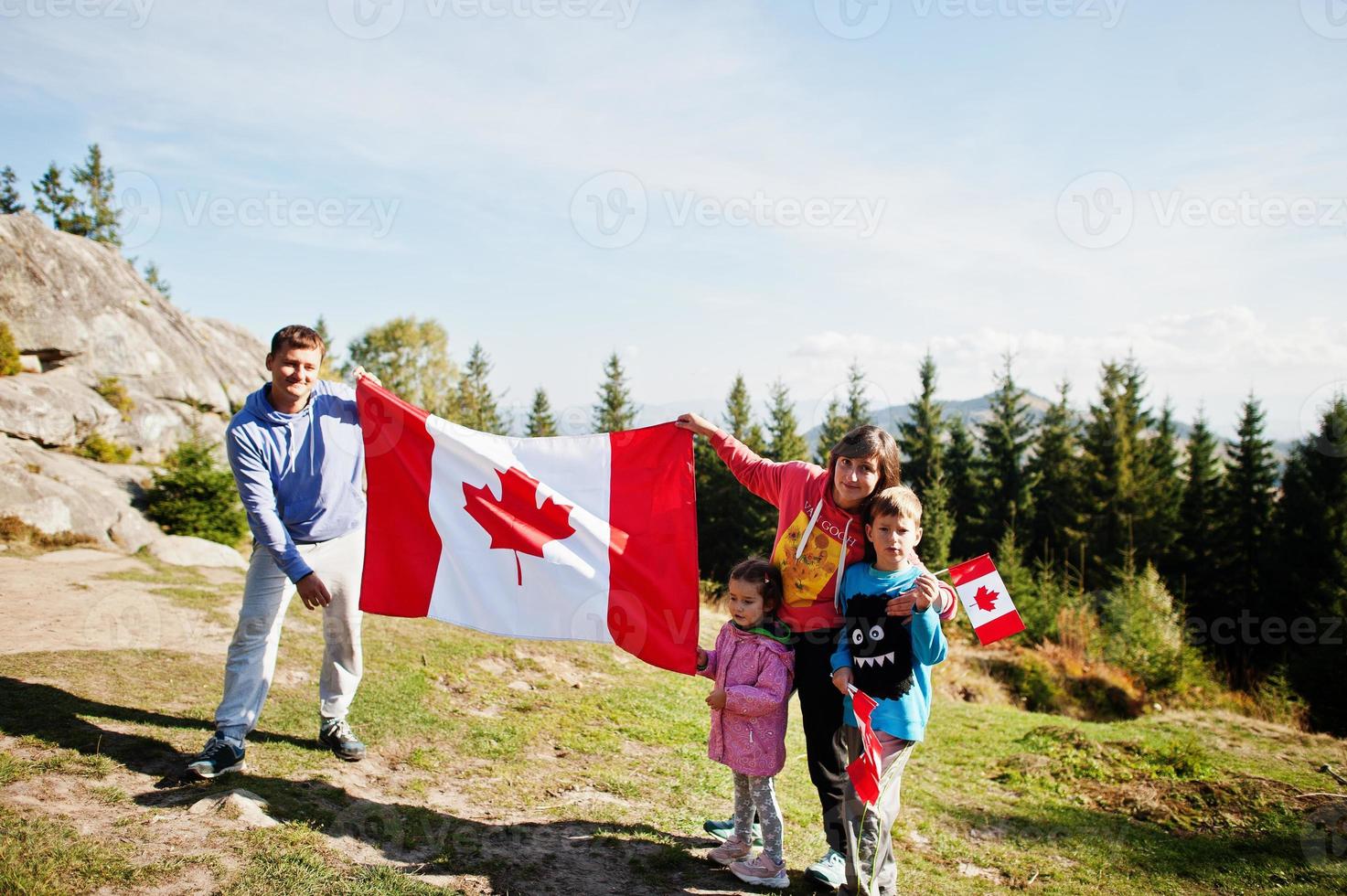 Happy Canada Day. Family with large Canadian flag celebration in mountains. photo
