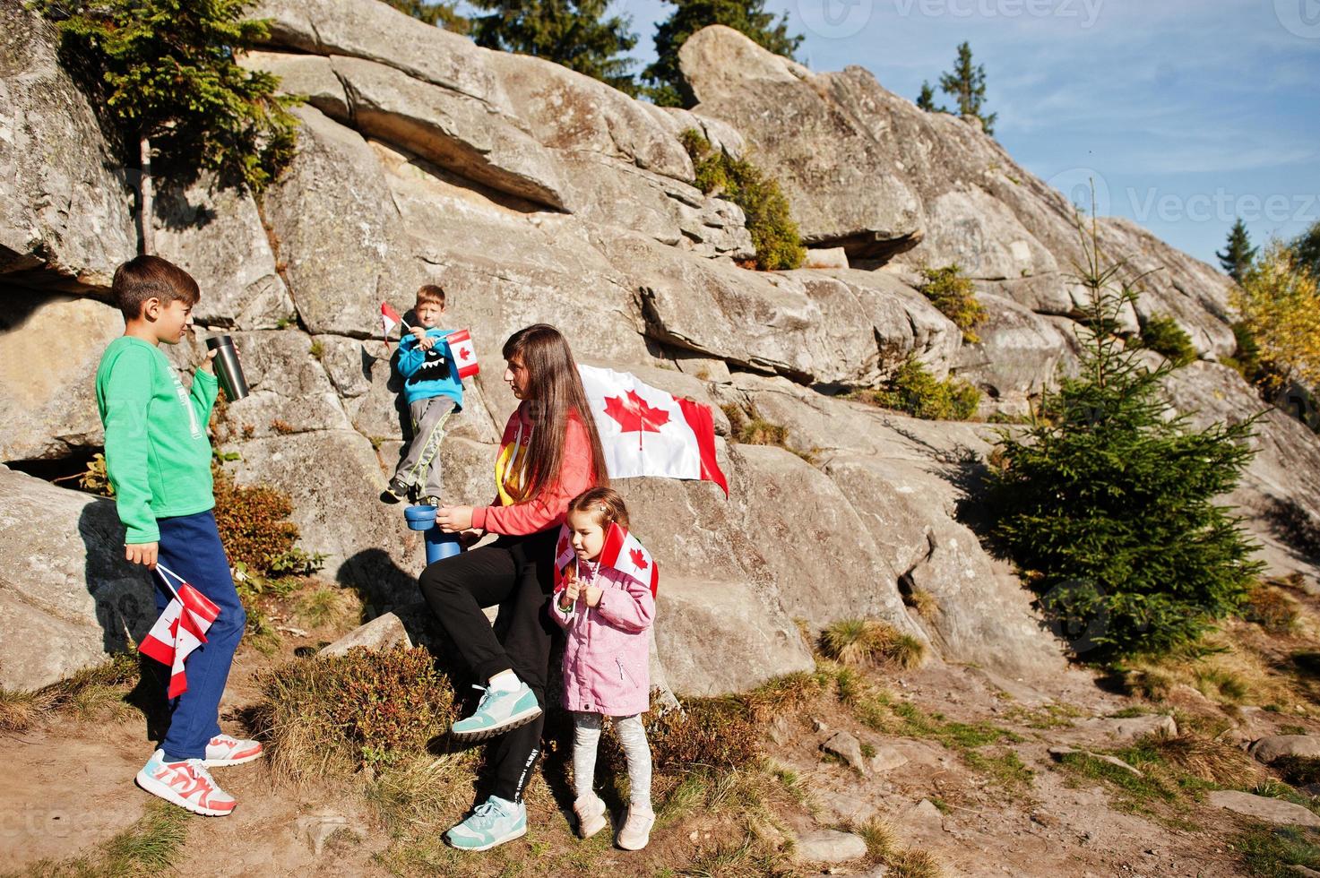 Happy Canada Day. Family of mother with three kids hold large Canadian flag celebration in mountains. photo