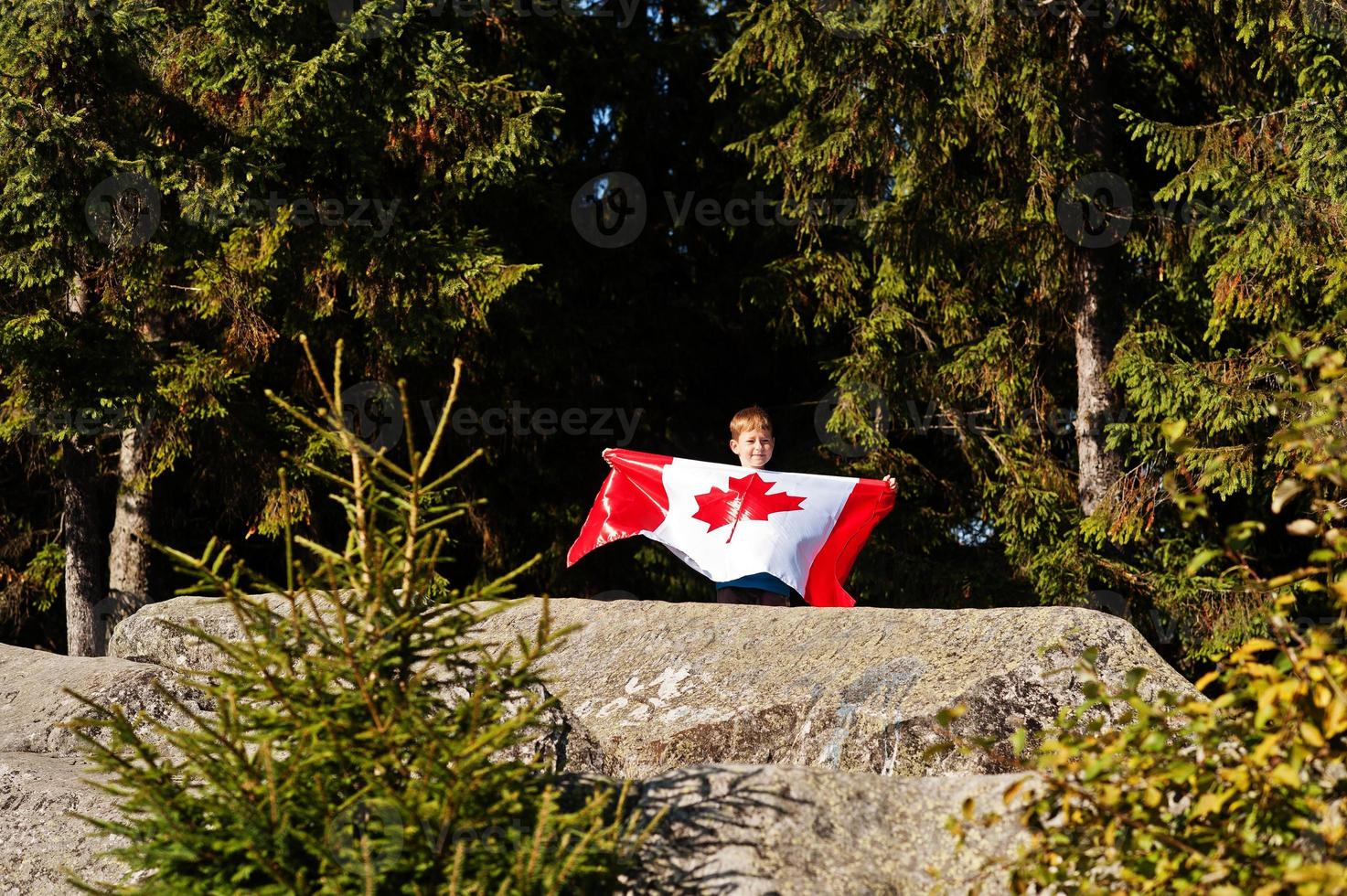 Happy Canada Day. Boy with large Canadian flag celebration in mountains. photo