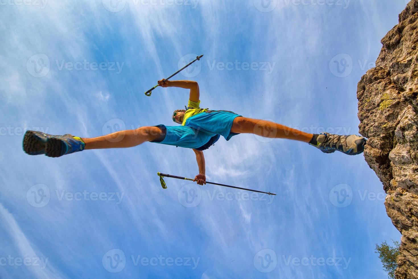 A trail running athlete jumps from a rock photo