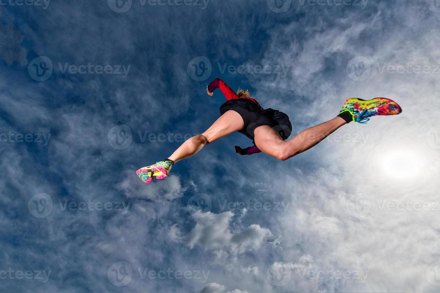 Athletic girl jumps while running in the mountains photo