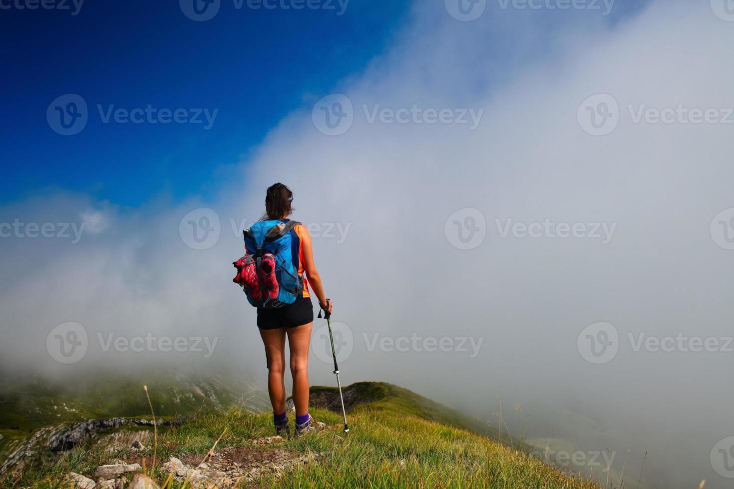 una niña mira lejos en la niebla en el valle de la montaña durante un paseo foto