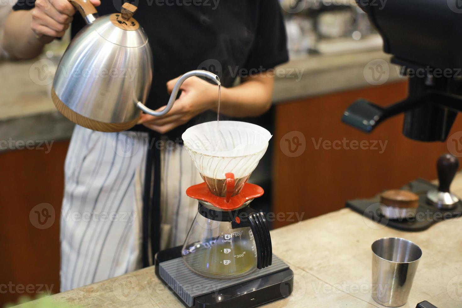 Women barista pouring water to make coffee using manual drip brewer. Hand drip coffee, Barista