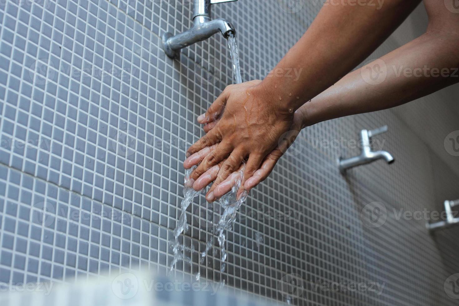 A moslem man take ablution, known as wudu, as one of ritual purification to pray. washing hand to prevent contracting corona virus photo