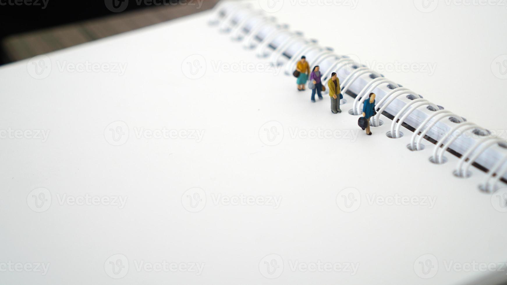 Miniature people in group walking on white blank Book. Business concept with copy space and white space for your text or design photo