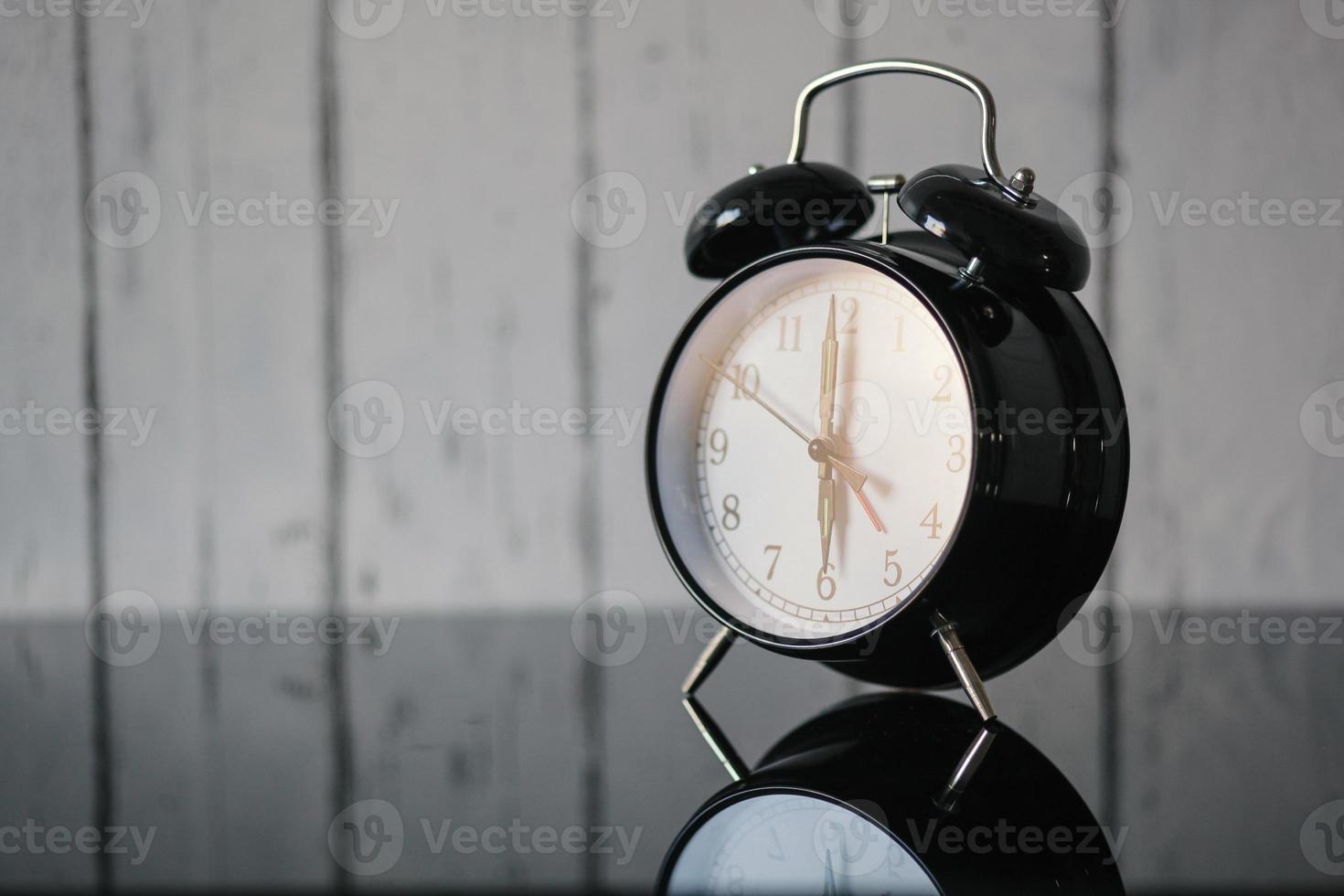 Alarm clock on glass table, wake up in the morning, vintage. Blur wall background photo