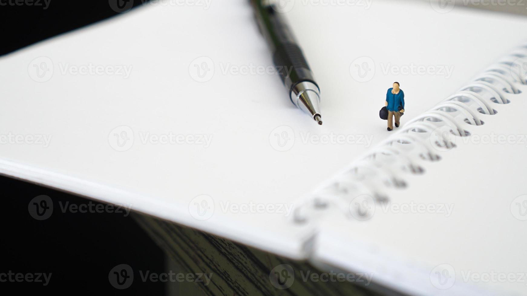 gente en miniatura caminando sobre un organizador blanco en blanco. concepto de negocio con espacio de copia y espacio en blanco para su texto o diseño foto