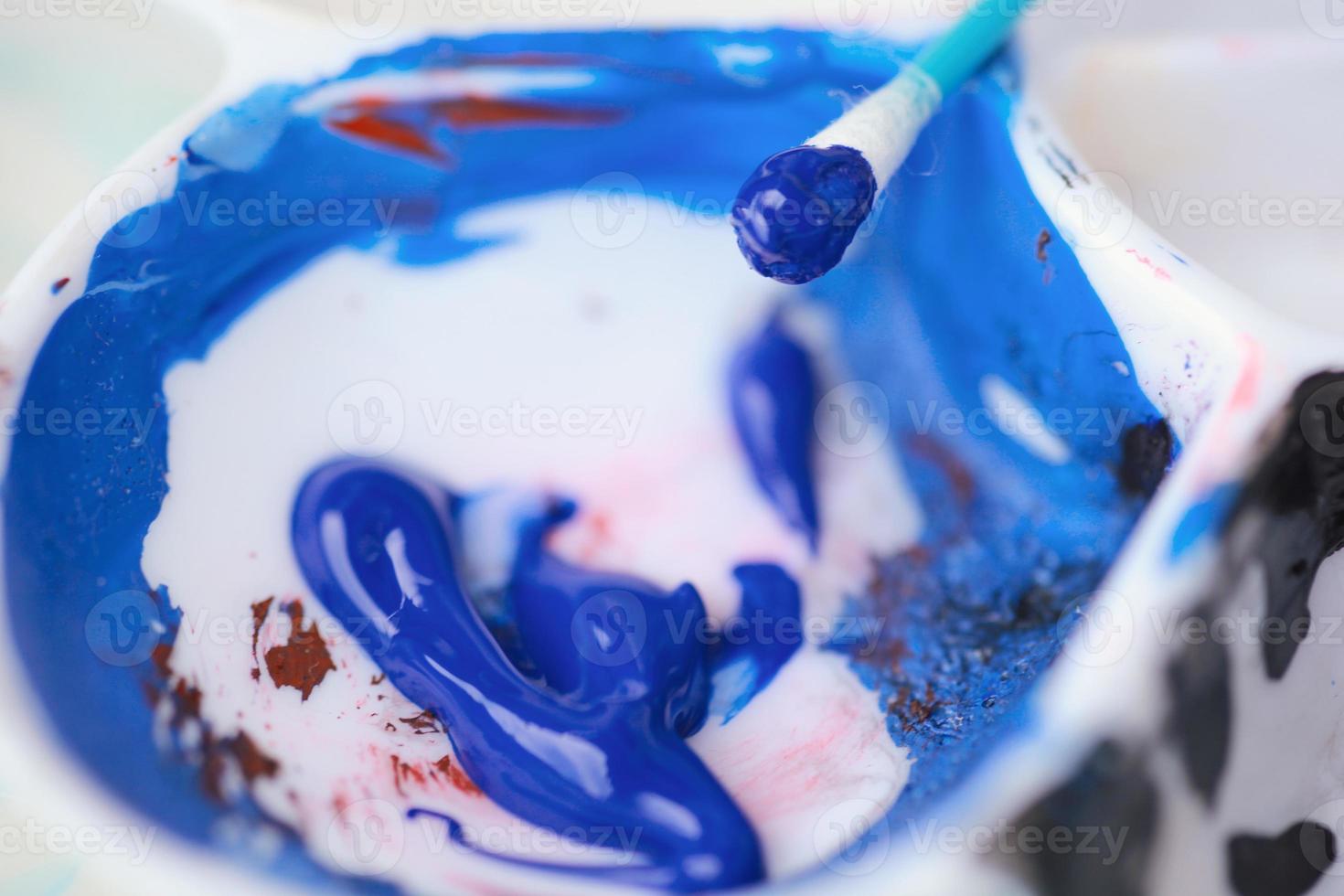 Close up view of a color pallet painting with blue and black paint photo