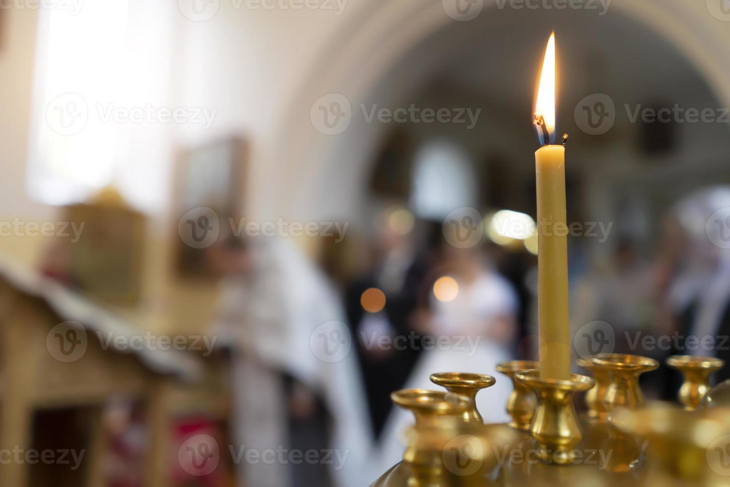 una vela encendida en una iglesia ortodoxa en el fondo de la acción foto