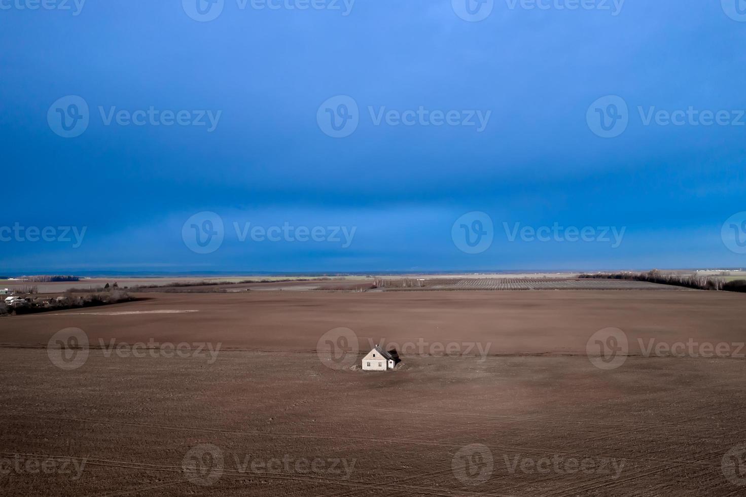 una casa abandonada en medio de un campo contra un cielo tormentoso. foto