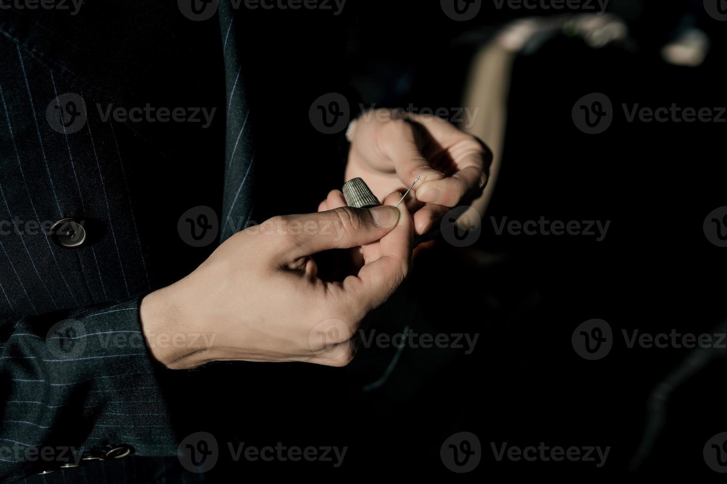 male tailor threads a needle photo