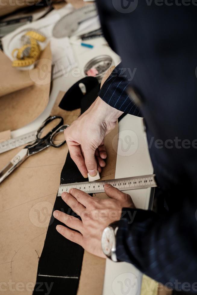 man seamstress makes pattern with chalk photo