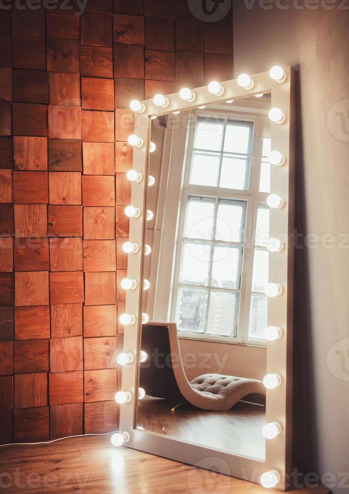 mirror with light bulbs against a wooden wall photo