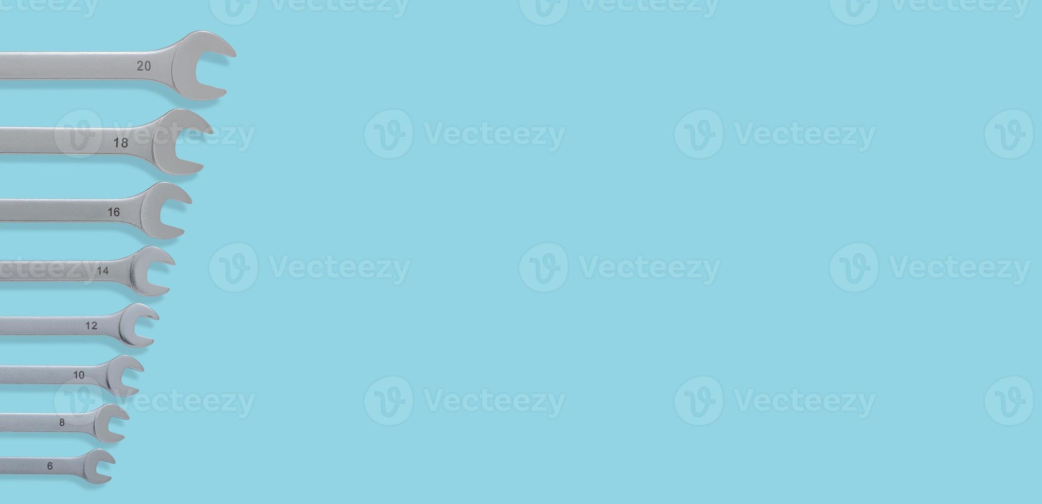 Banner with a set of workshop wrenches of different size with shadows at solid turquoise background with copy space. Concept of hardware, gears, and workshop workflow. photo