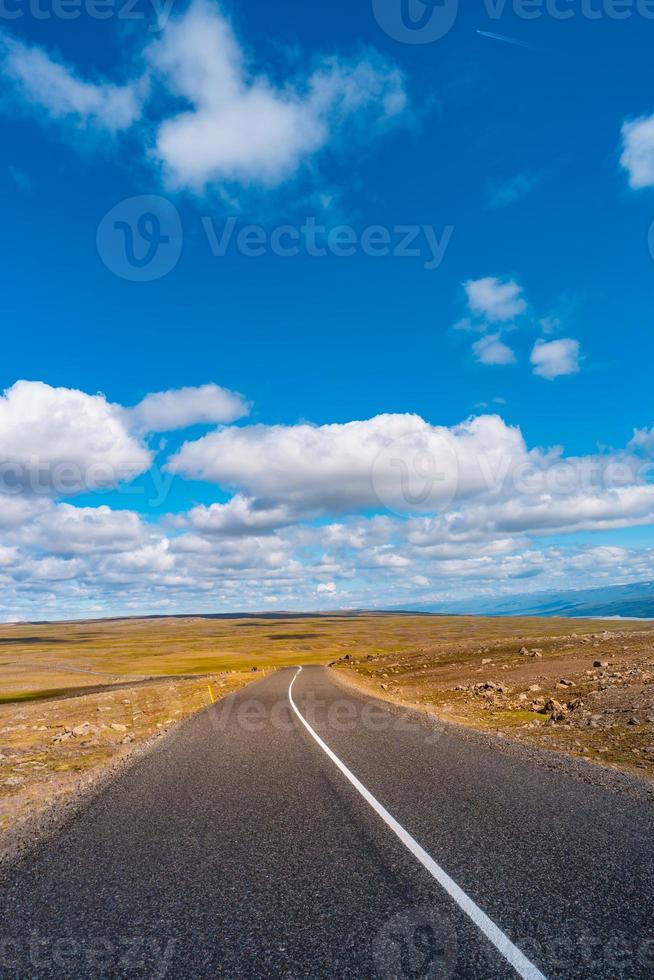 Highland landscape in Iceland, with paved asphalt road at summer sunny day and blue sky with clouds. photo