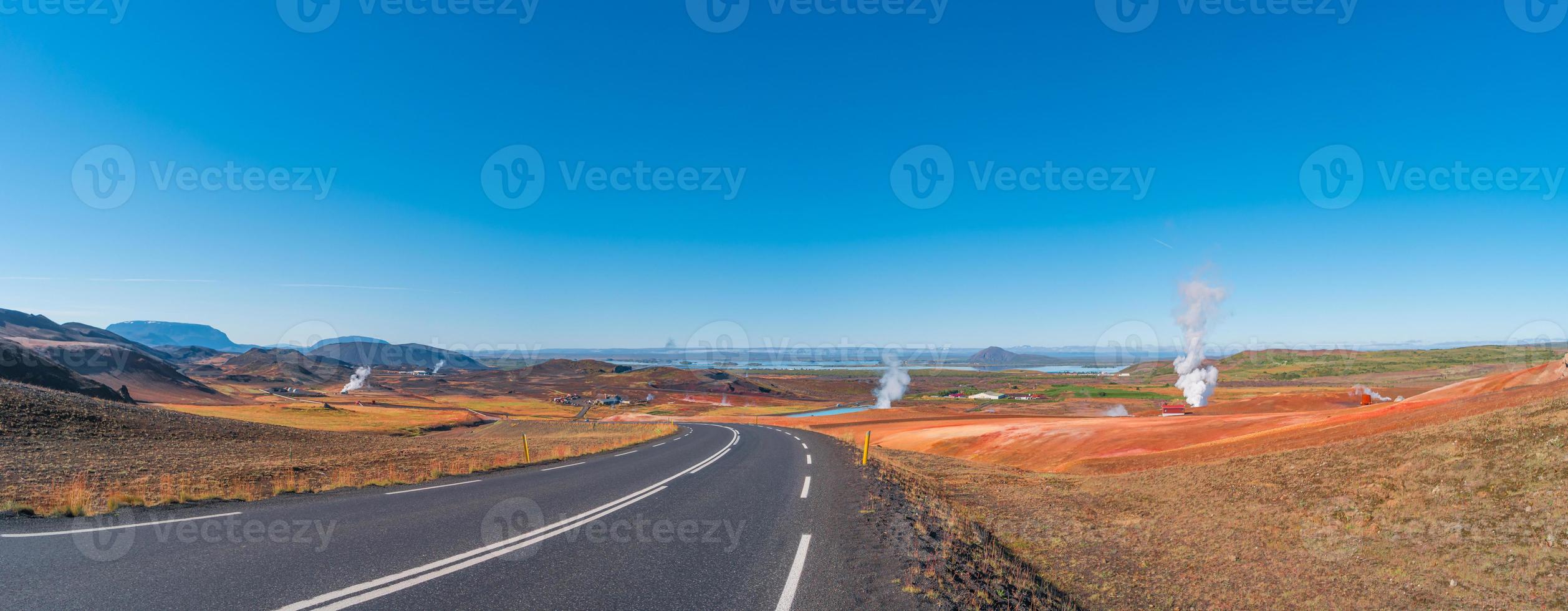 Paved Ring road going through volcanically active zone Hverir near Myvatn lake in Highlands of Iceland, resembling Martian red planet landscape, at summer and blue sky. photo