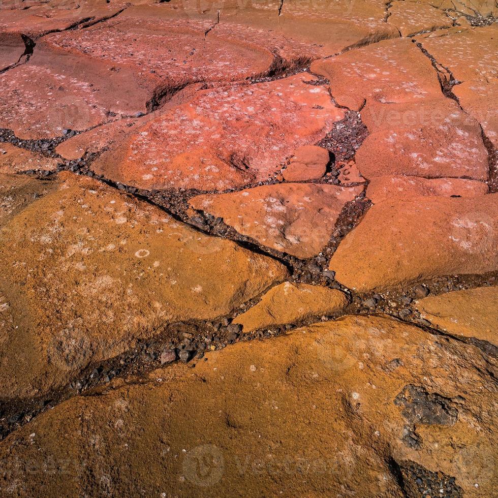 Colorful volcanic rocks with red and turquoise volcano soil with cracks and patterns as background. photo