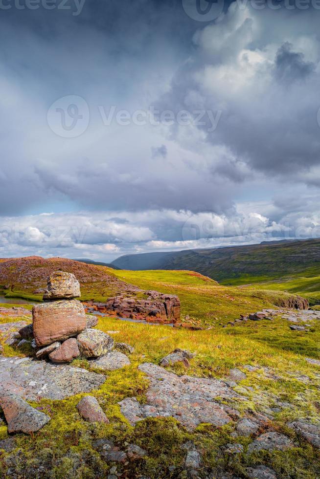 Lonely cairn, a pile of stone, a landmark for navigation in Highlands of East Iceland at summer day and dramatic cloudy sky. photo