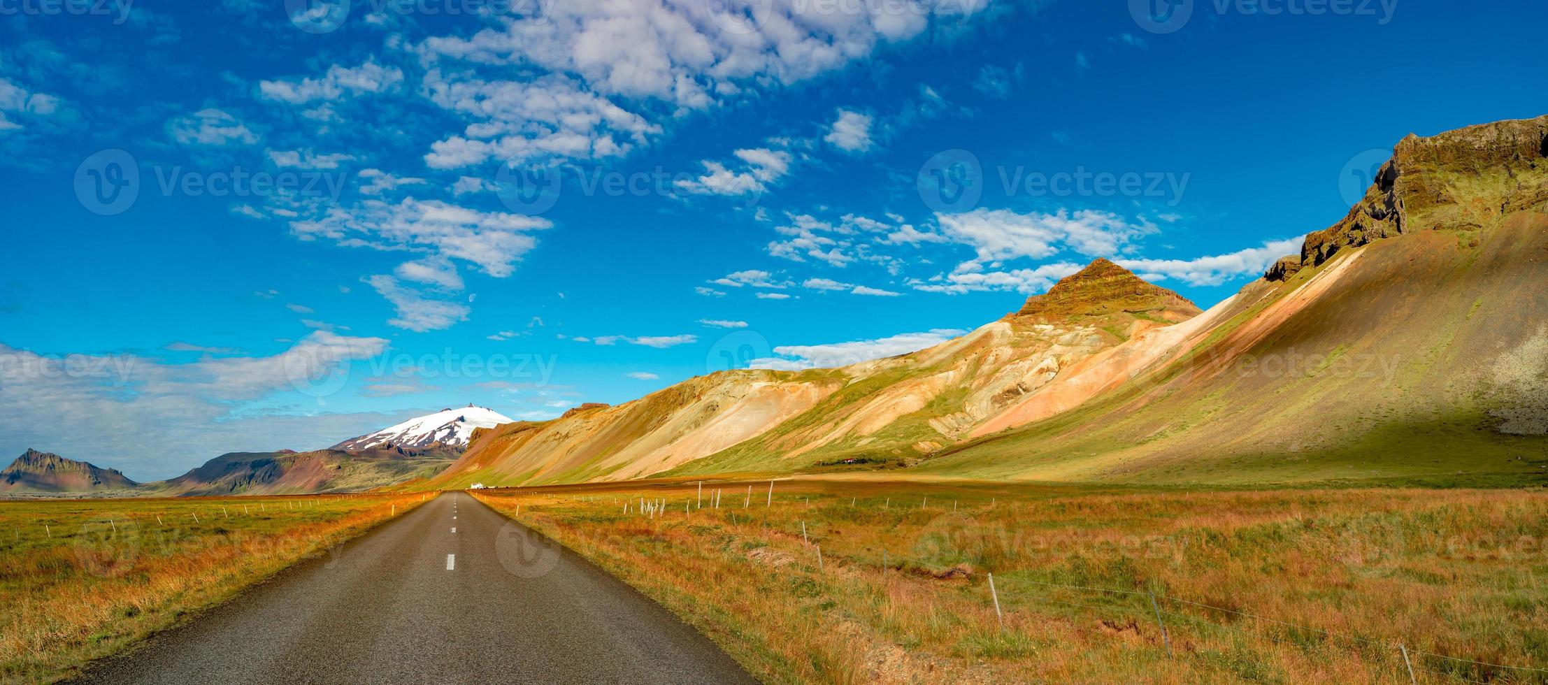 Panoramic view over asphalt road towards Snaefellsjoekull mountain volcano peak and Icelandic colorful and wild landscape at summer time and blue sky, Iceland. photo