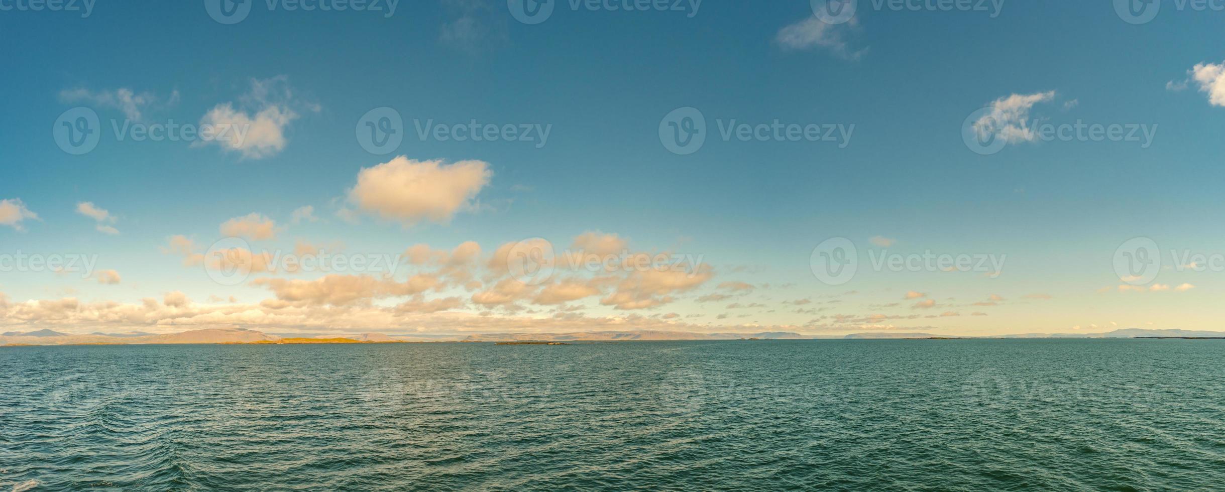 Panoramic view over remote islands in Atlantic ocean on the way to Iceland at summer time, during warm sunset with beautiful clouds. photo