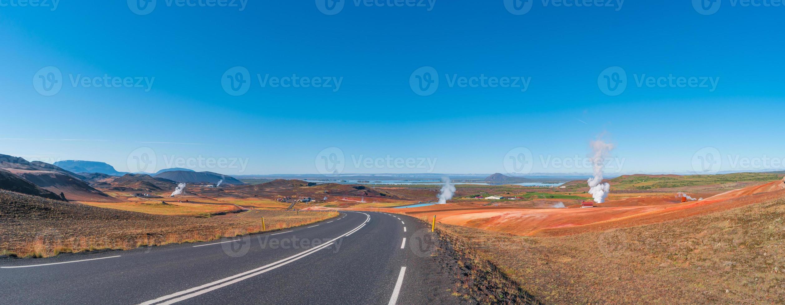 Paved Ring road going through volcanically active zone Hverir near Myvatn lake in Highlands of Iceland, resembling Martian red planet landscape, at summer and blue sky. photo