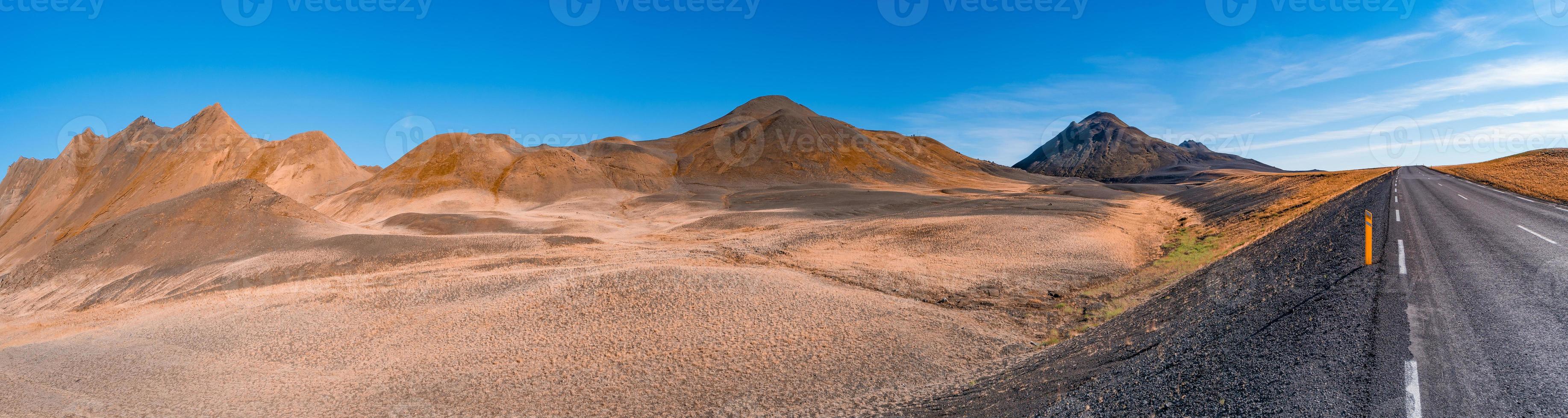 Panoramic view over volcanically active zone in Highlands of Iceland, resembling Martian red planet landscape, with black volcano and road, at summer and blue sky. photo