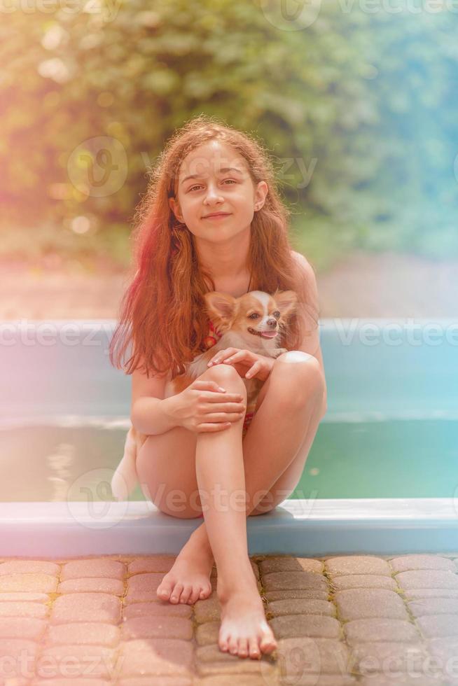 Vacation with a pet. Cute girl 10 or 11 years old with her dog by the pool. photo