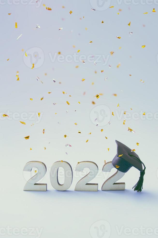 Graduation 2022 wearing graduate hat on a wooden 2022 number with flying confetti photo
