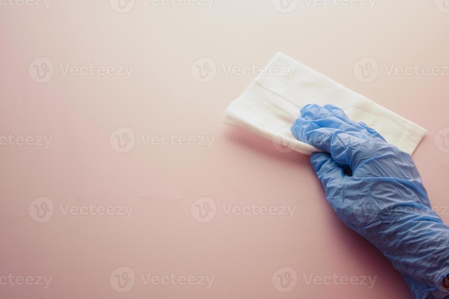 hand in blue rubber gloves cleaning table with cloth photo