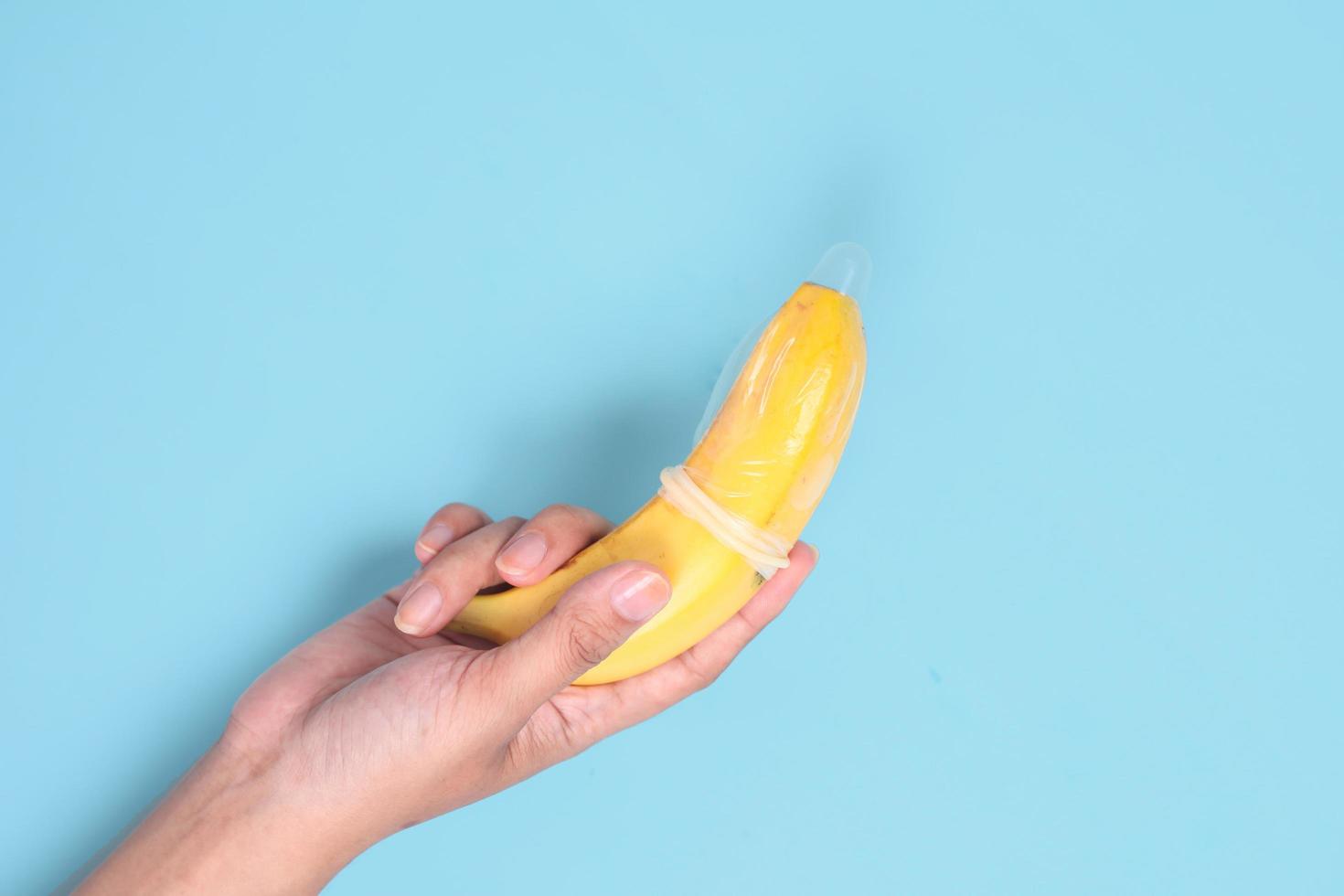 educational sex with banana in hand isolated on blue background photo