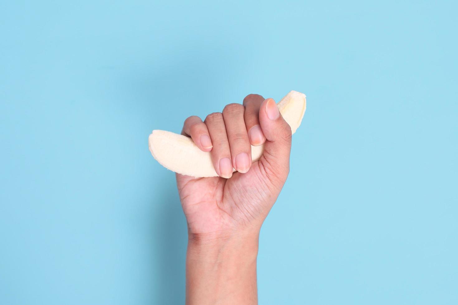 sexo educativo con plátano en la mano aislado sobre fondo azul foto