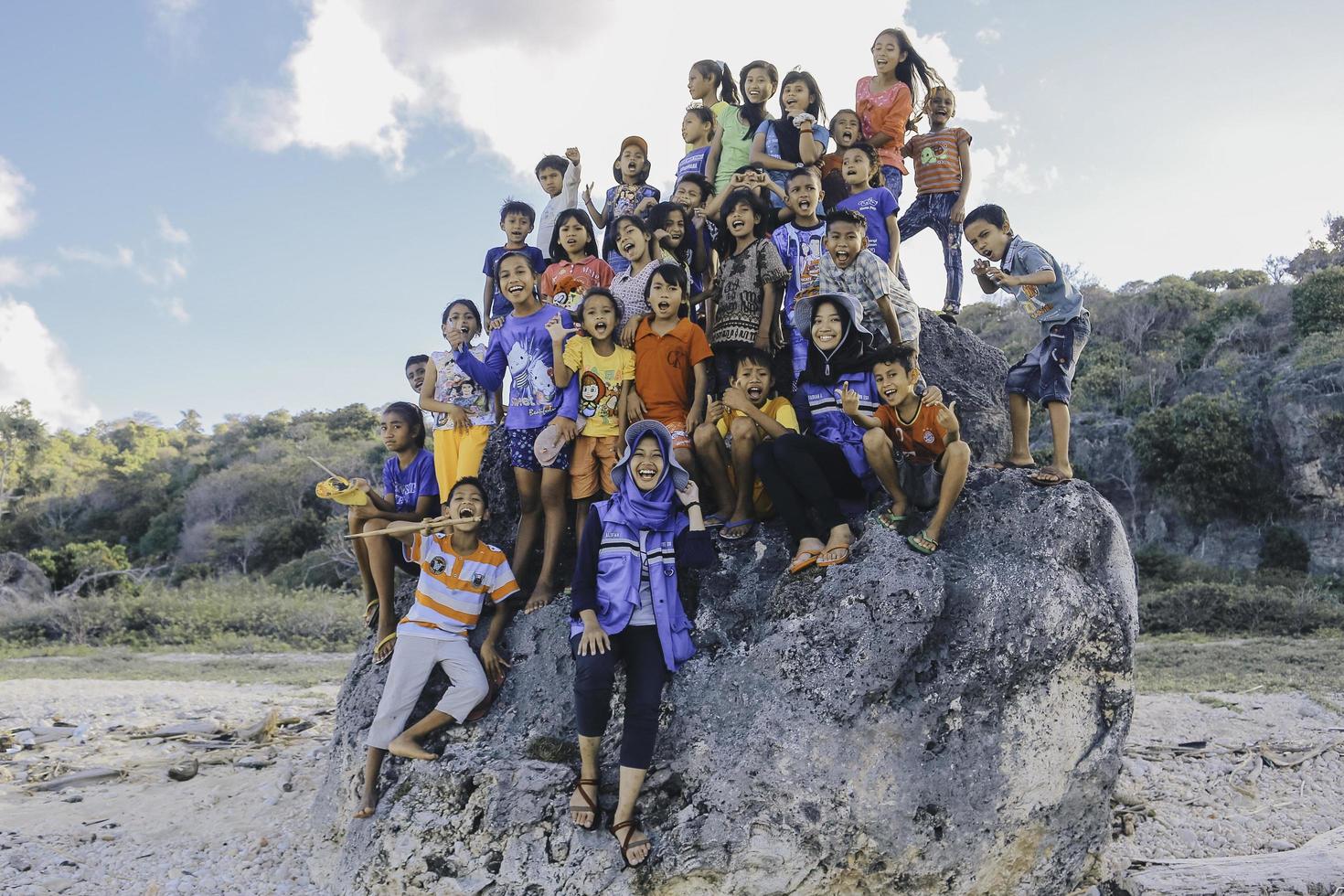 East Nusa Tenggara Indonesia Kids are cheering together enjoy playing in the big rock on the beach. NTT ROTE, INDONESIA - April, 2020. photo