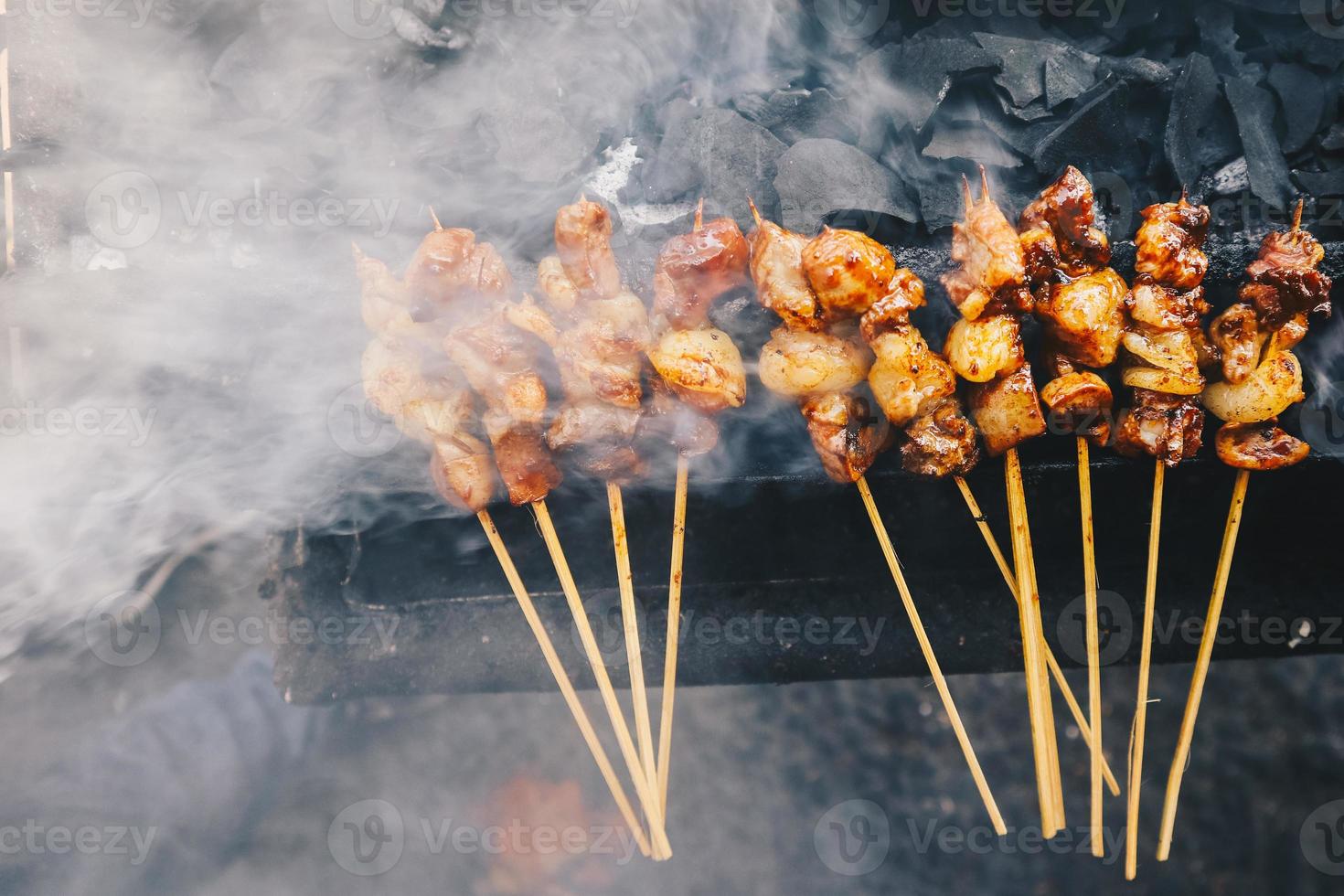 satay de cabra en fuego rojo asado por personas. comida tradicional indonesia hecha de cordero. foto