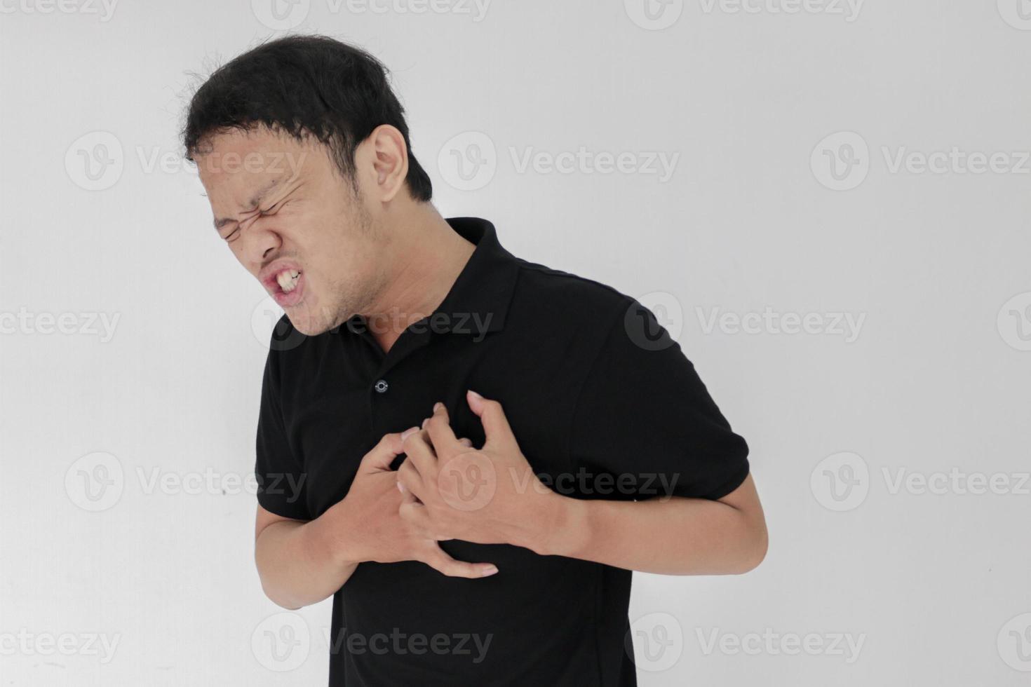 ataque al corazón o corazón roto de un joven asiático con una emoción herida que usa camisa negra foto