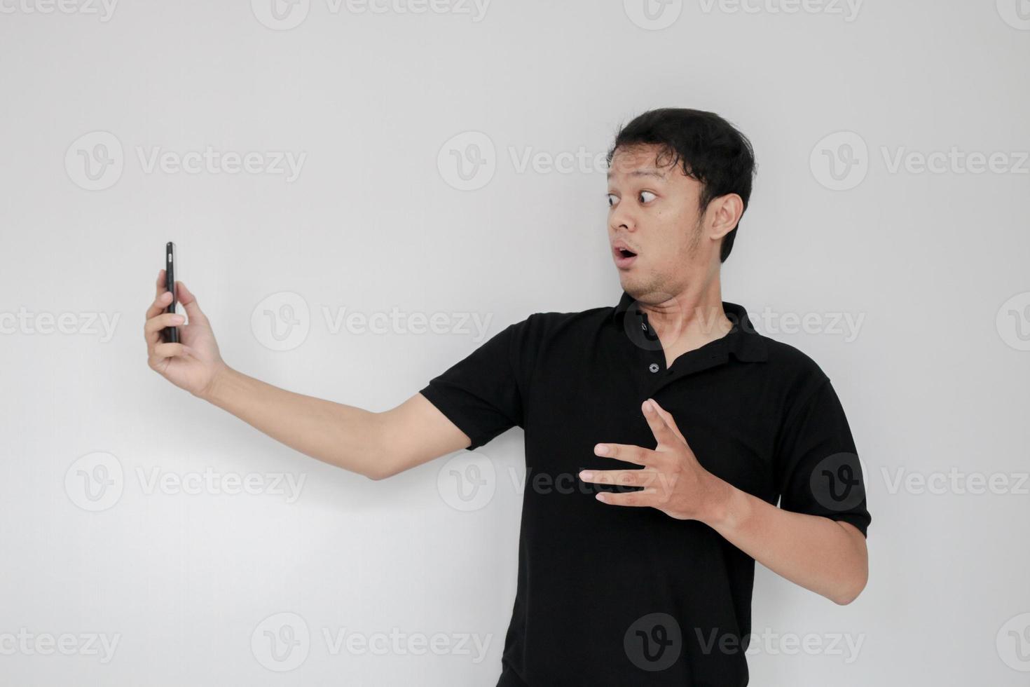 Wow face of Young Asian man shocked what he see in the smartphone on isolated grey background. photo