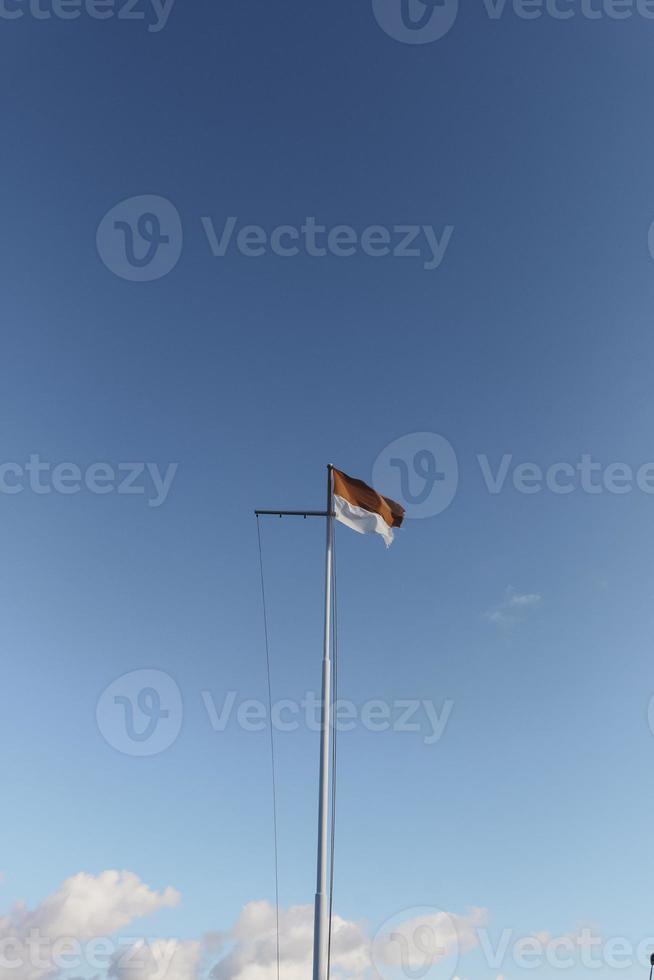 bandera de indonesia en el mástil de acero sobre fondo de cielo azul foto