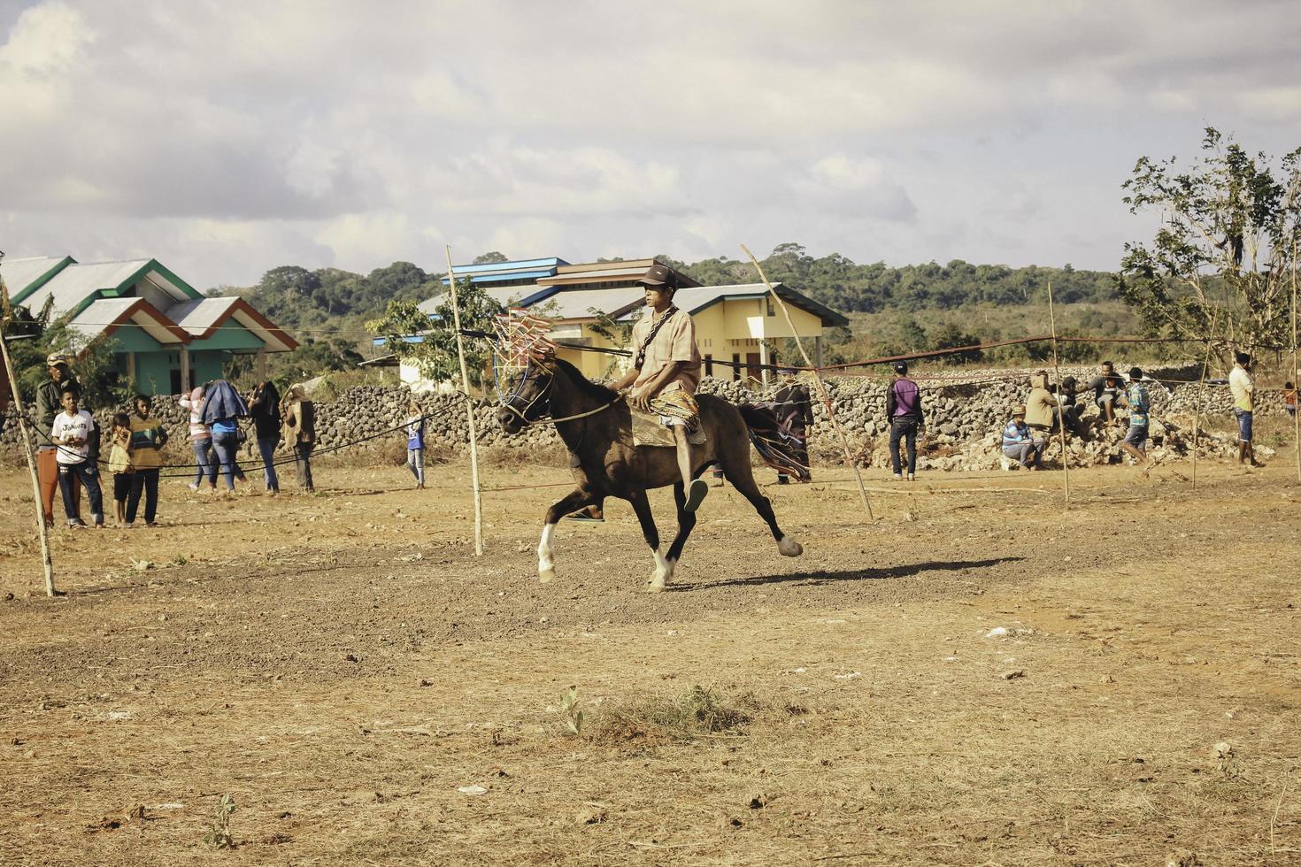 A man horse rider with Tilangga Traditional hat on horse ready to race culture from Rote Island, East Nusa Tenggara, Indonesia. Rote, Indonesia - March 23, 2020 photo