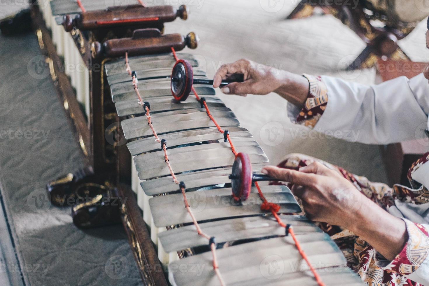 una mano de hombre usa batik jugando género gamelan o slenthem. foto